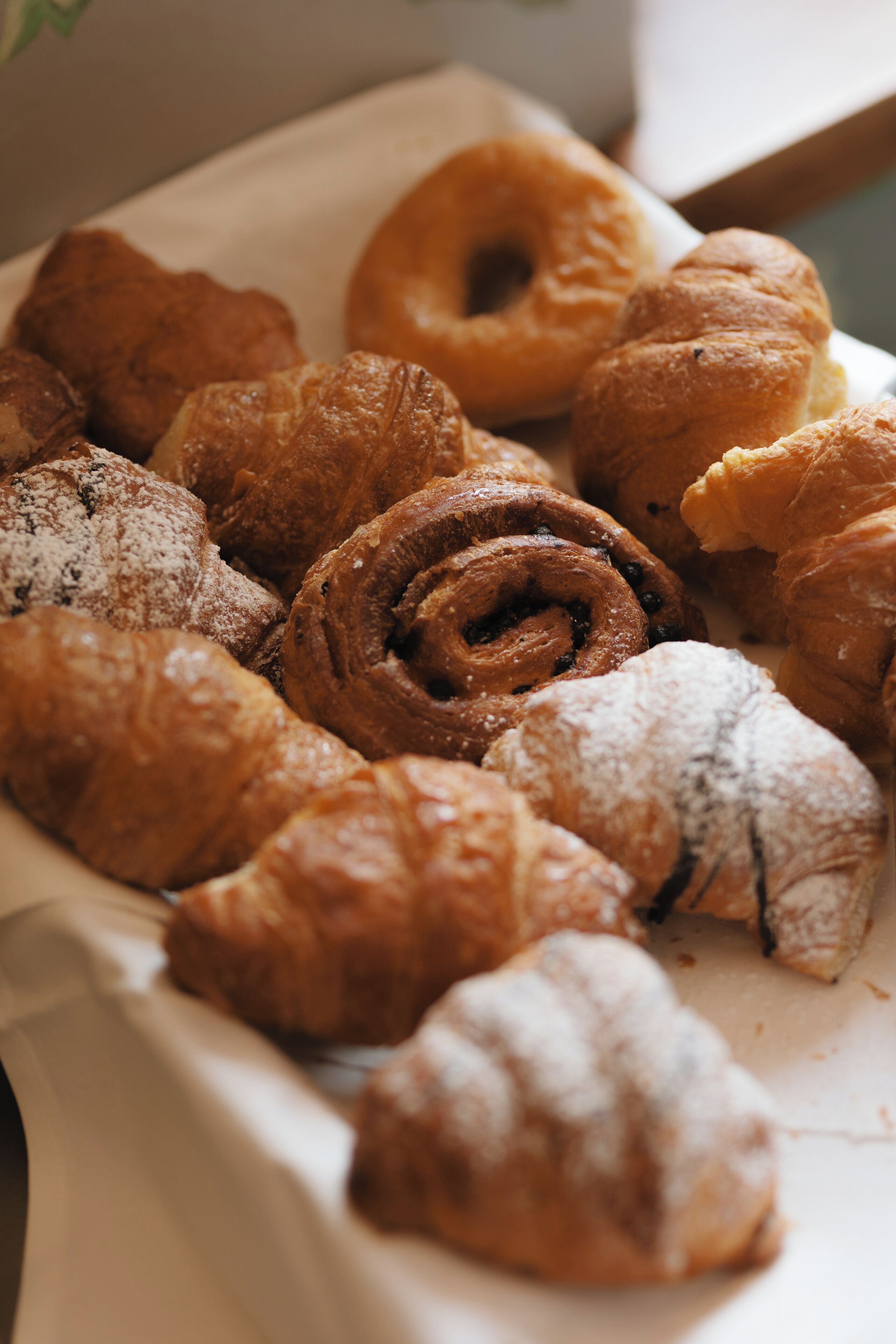 A variety of pastries including croissants and donuts on a tray.