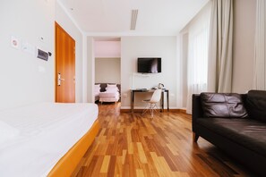A hotel room with a bed, a desk with a chair, a leather sofa, and a television on the wall. - Hotel Miramare (Civitanova Marche)