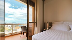 Een hotelkamer met een groot raam, een bed, een stoel en een nachtkastje.