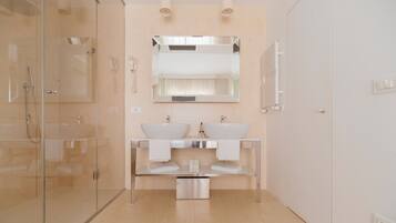 A modern bathroom with a glass shower enclosure, two sinks with mirrors above, and a towel rack.
