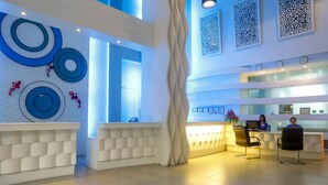 Een moderne receptiezone met een kleurenpalet van wit en blauw, een receptiebalie en een decoratieve wand met cirkelvormige patronen.