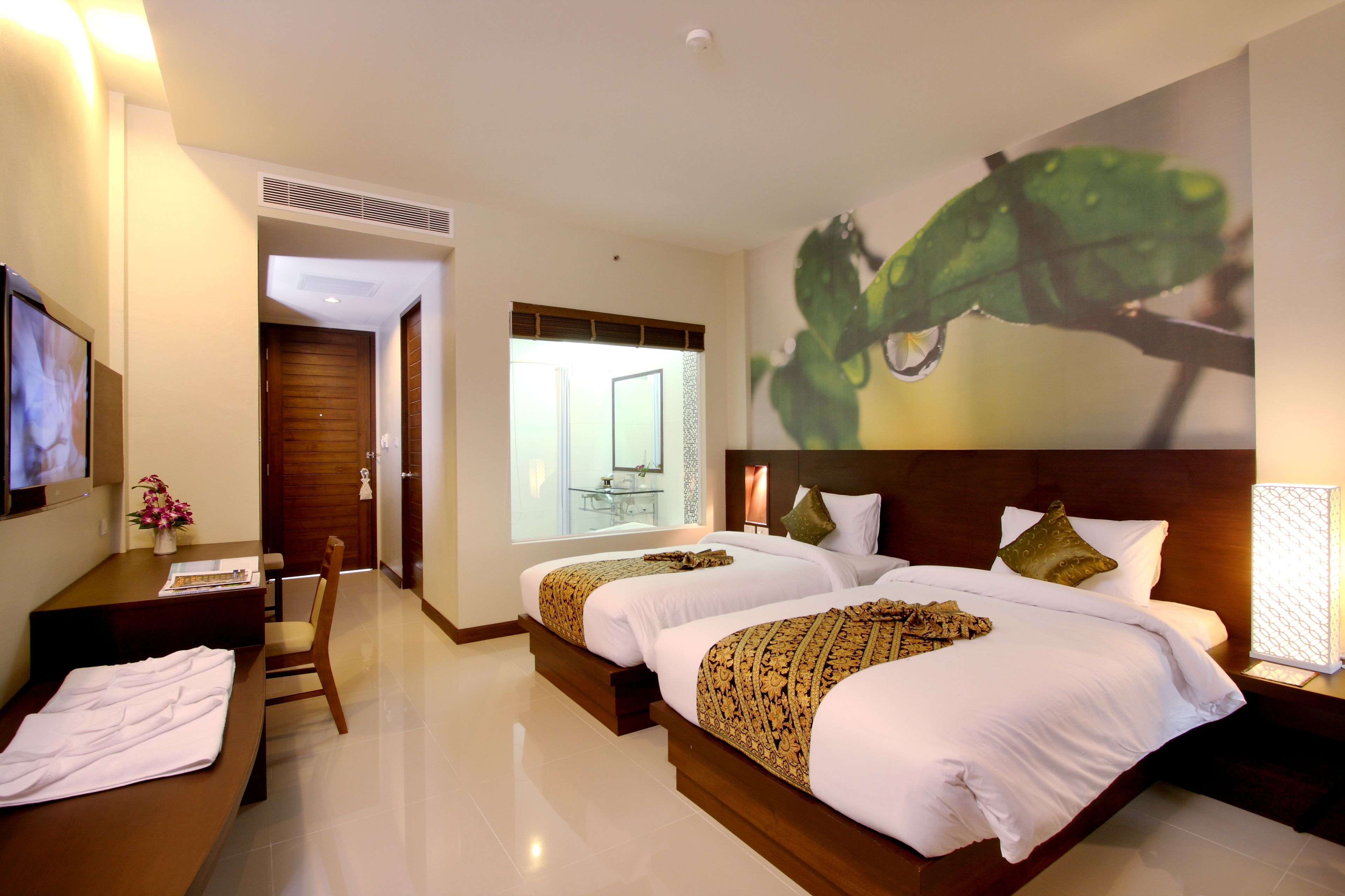 A hotel room with two beds, a desk, and a chair.