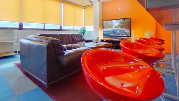 Una sala de estar moderna con un sofá, una televisión y sillas rojas.