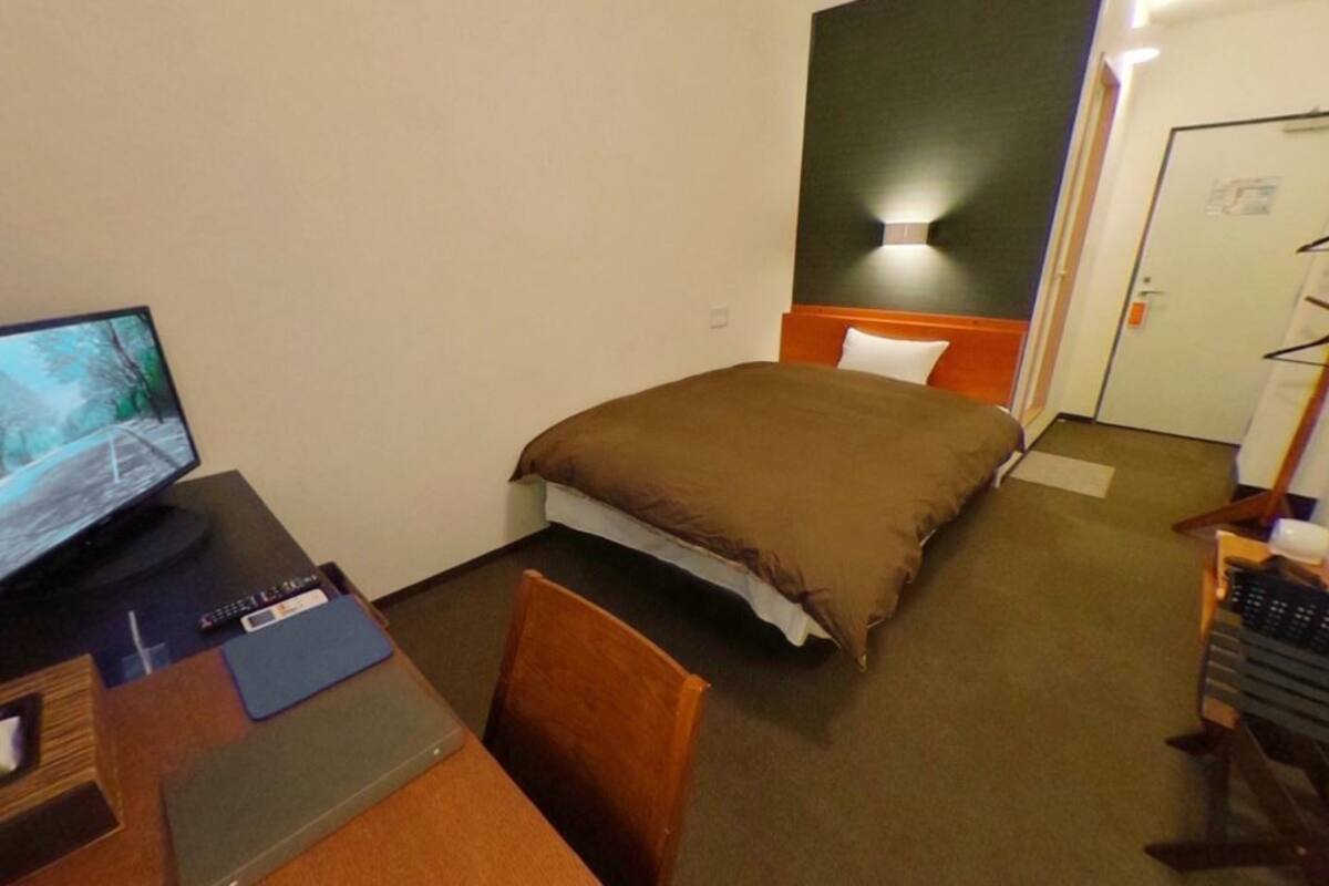 Une chambre d’hôtel avec un lit, un bureau avec un ordinateur et une chaise.