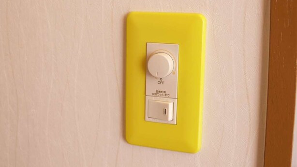 Un interrupteur électrique jaune sur un mur de couleur claire.