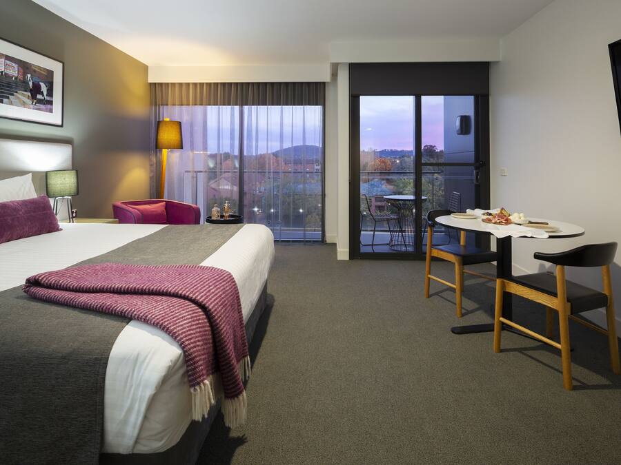 Ett hotellrum med en säng, ett skrivbord och en balkong med utsikt.