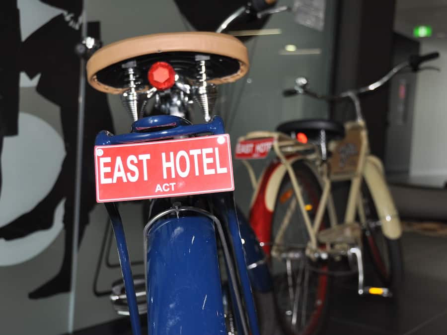 A bicycle with a sign that reads "EAST HOTEL ACT."