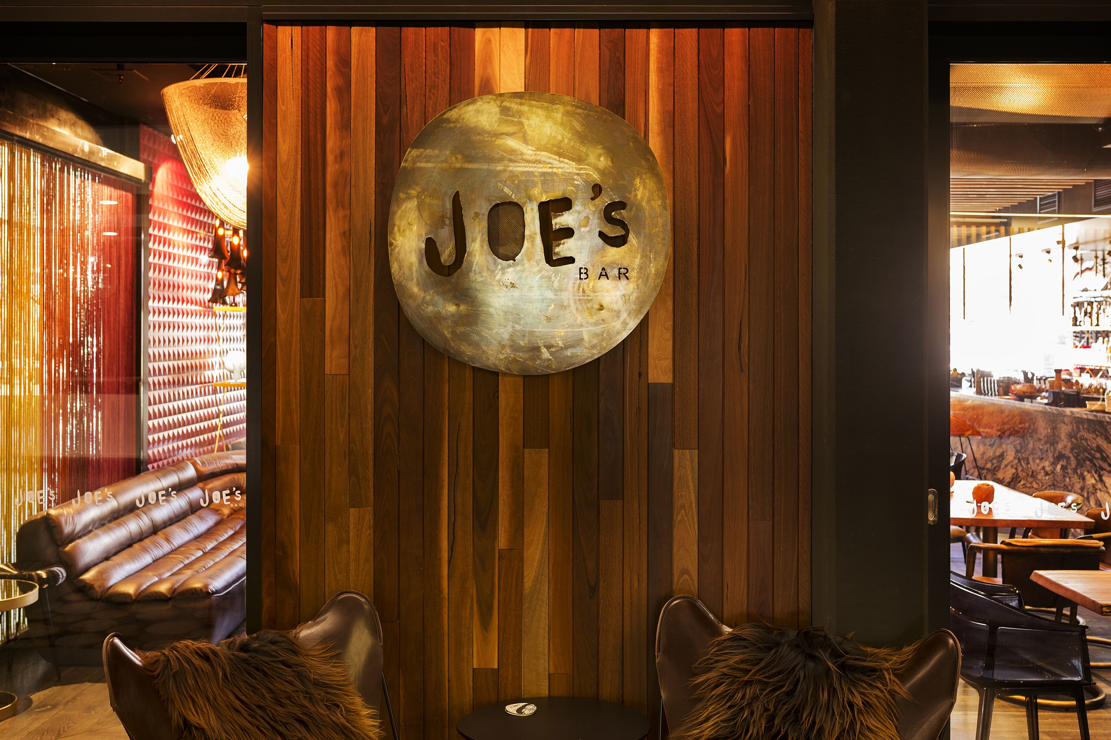 A bar named "JOE'S BAR" with a wooden wall and a large spherical sign.