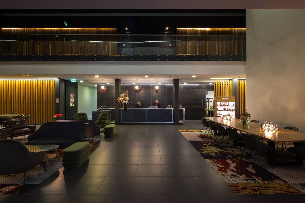 En modern hotellobby med en receptionsdisk, en sittgrupp och ett matbord.
