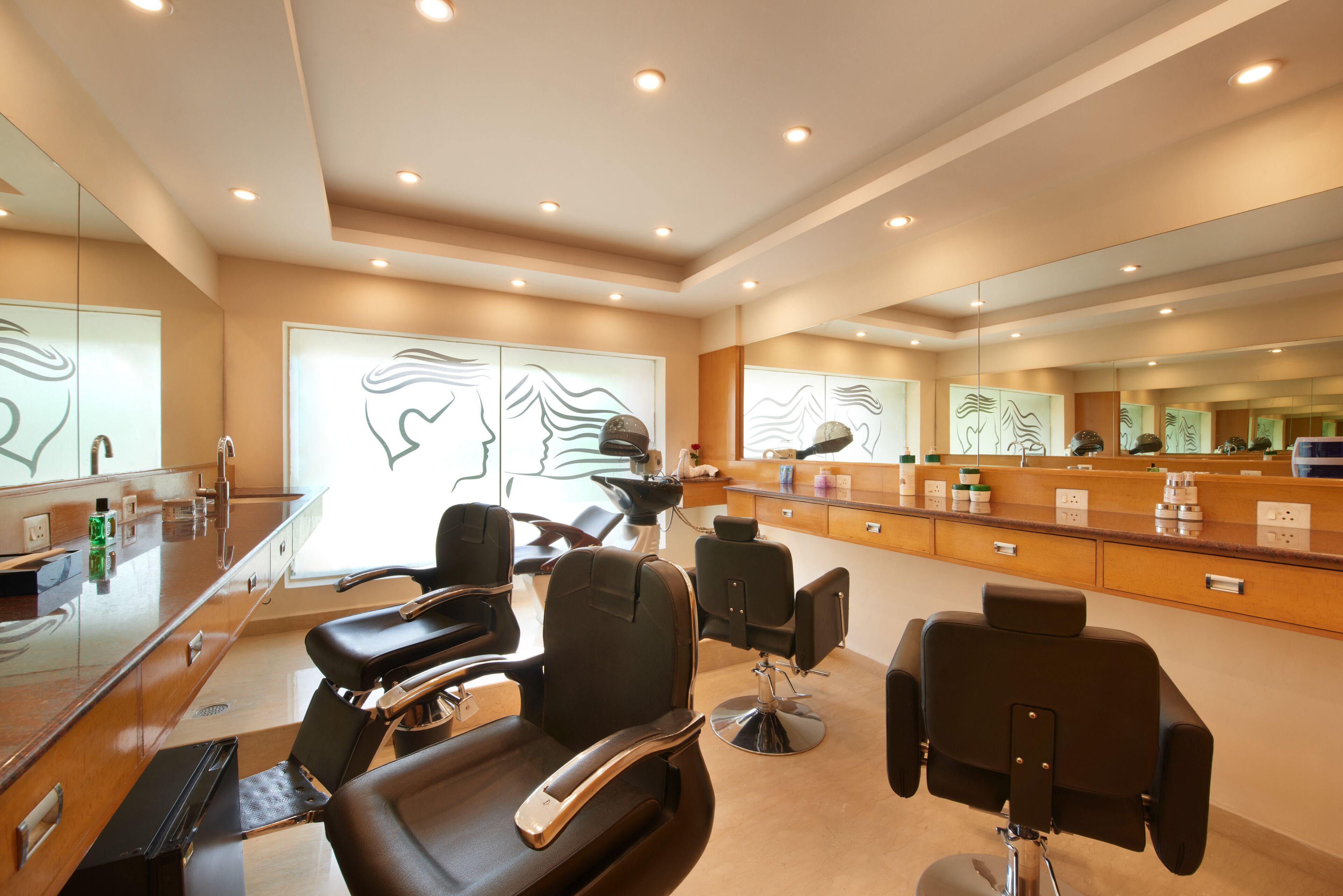 A modern hair salon with multiple seating areas, a reception desk, and a large mirror wall.