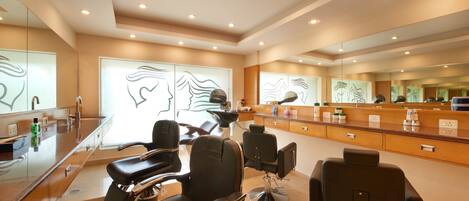 A modern hair salon with multiple seating areas, a reception desk, and a large mirror wall.