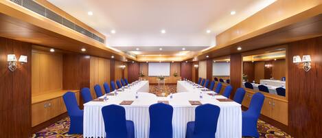 A conference room with a long table, blue chairs, and a patterned carpet.