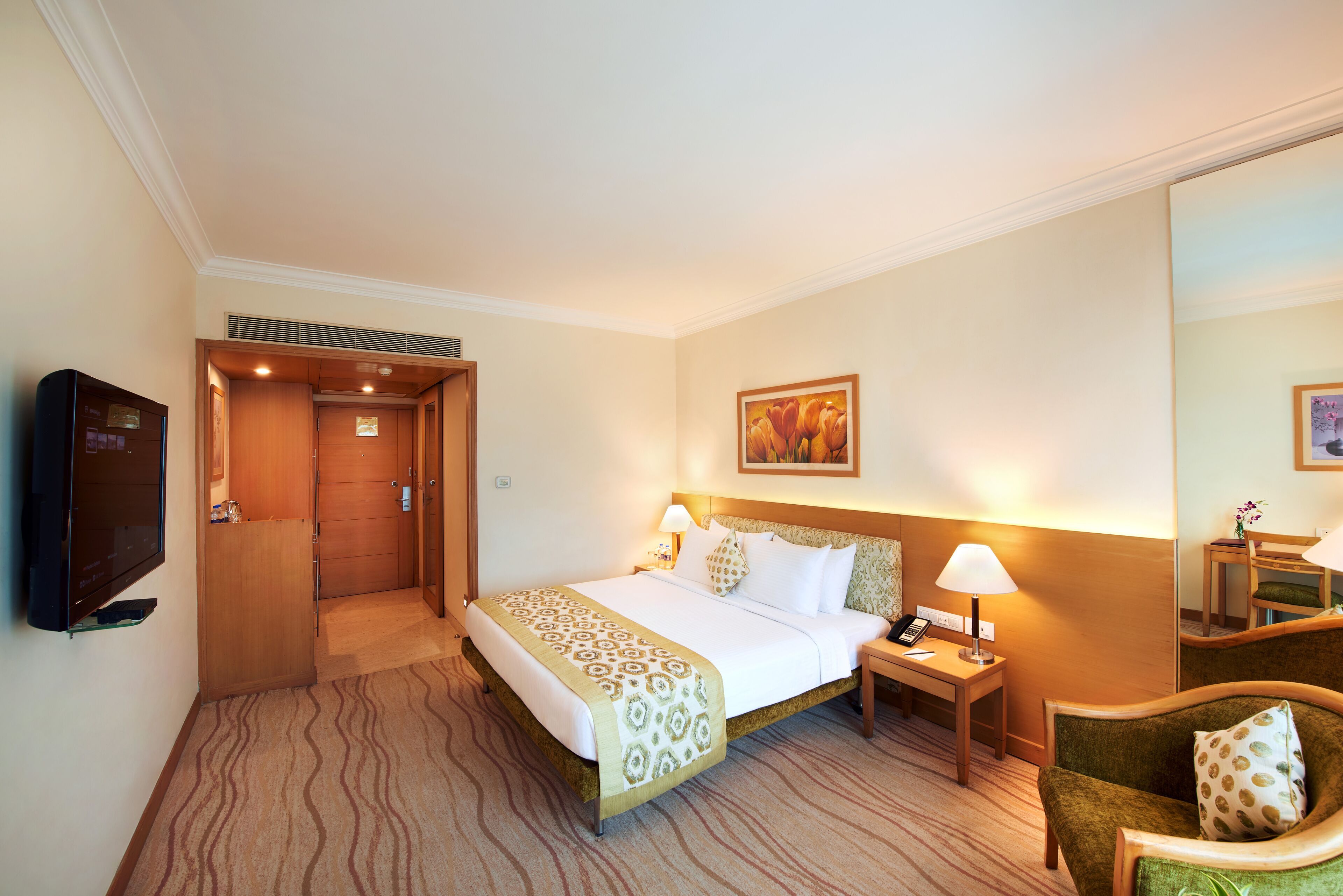 Une chambre d’hôtel comprenant un lit, une table de chevet, une lampe, une chaise et un téléviseur.