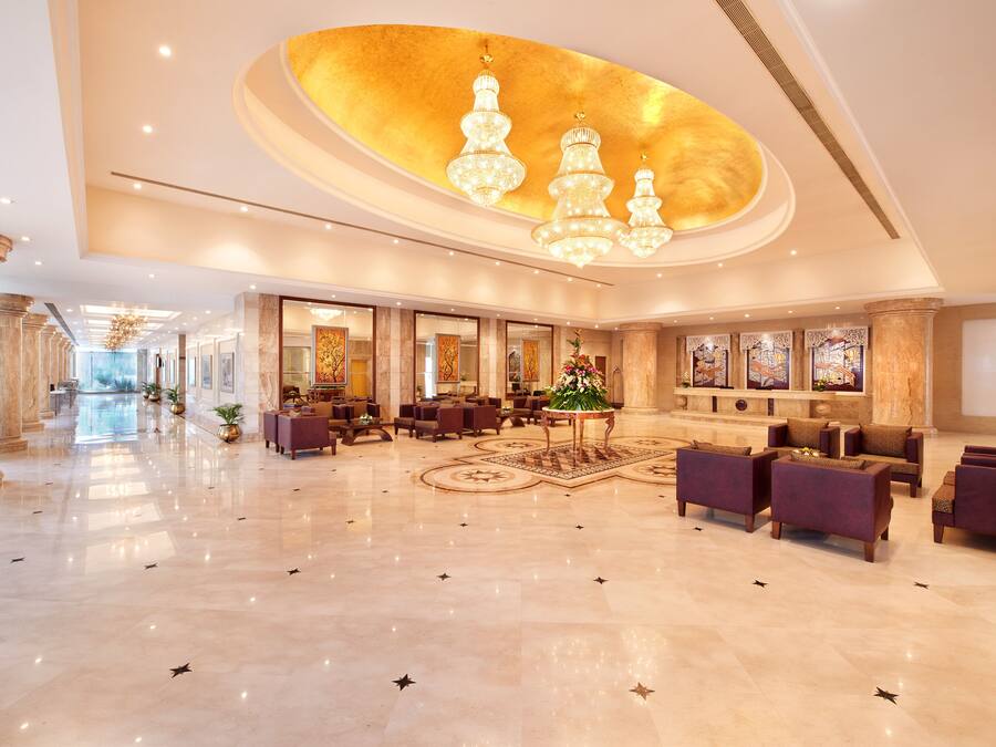 A spacious lobby with a marble floor, multiple seating areas, and a large chandelier.
