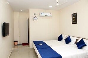 A hotel room with a bed, a TV, an air conditioning unit, and a ceiling fan.