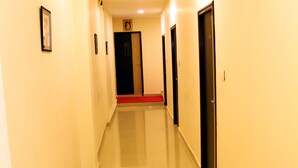 A long, narrow hallway with doors on both sides, leading to a dark room at the end. - KEK Accommodation (Chennai)