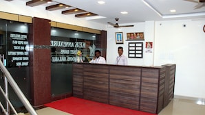 A hotel reception desk with a red carpet, wooden paneling, and a ceiling fan. - KEK Accommodation (Chennai)