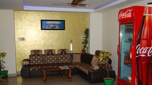 A living room with a sofa, a coffee table, a red Coca-Cola refrigerator, and a wall-mounted picture. - KEK Accommodation (Chennai)