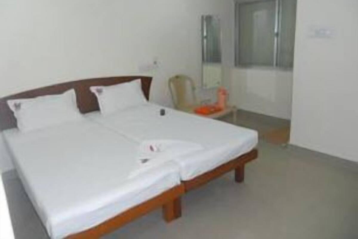 A hotel room with a double bed, a chair, a small table, and a window.