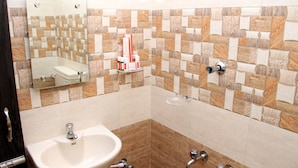 A bathroom with a white sink, a mirror, and a tiled wall with a geometric pattern. - KEK Accommodation (Chennai)
