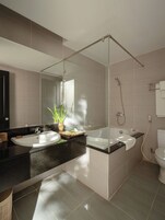 Un baño moderno con un espejo grande, una bañera y una ducha.