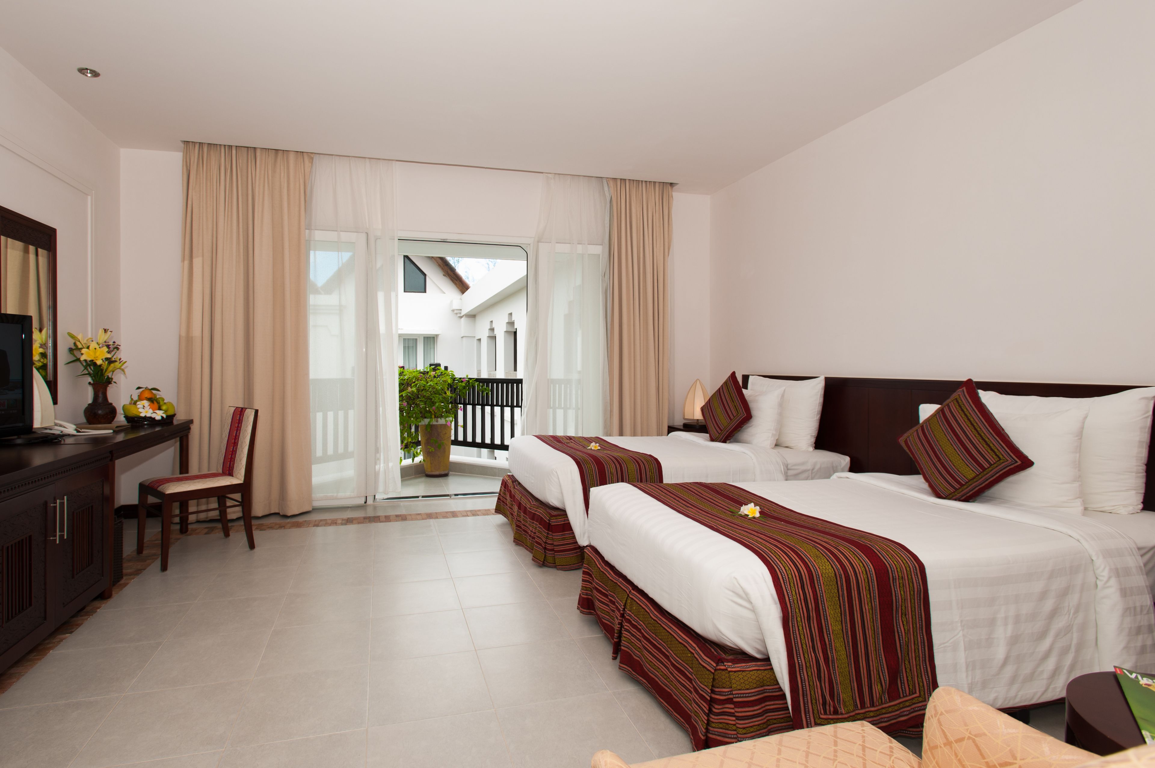 Een hotelkamer met twee bedden, een televisie, een bureau en een balkon met uitzicht.