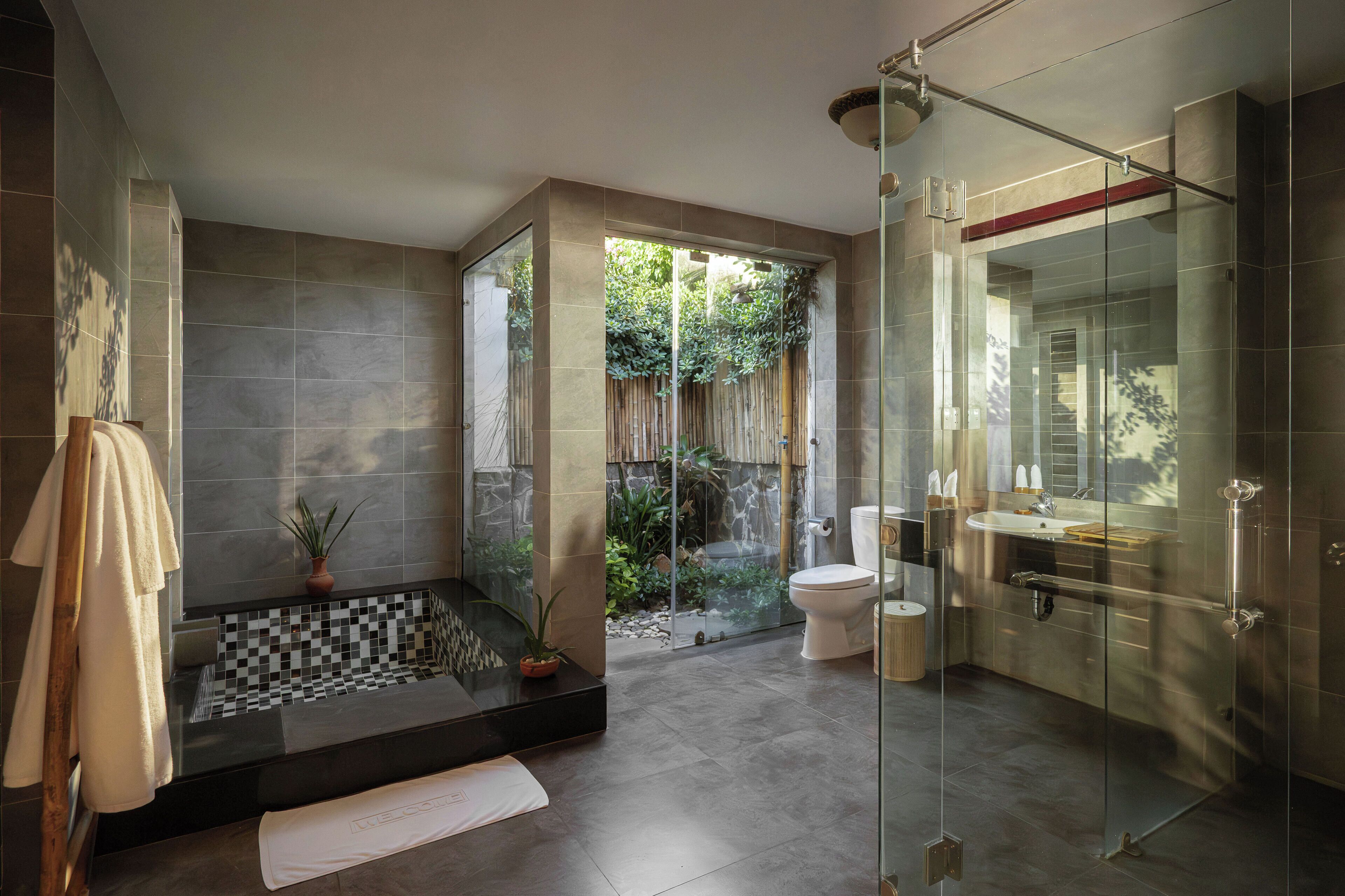 A modern bathroom with a glass-enclosed shower, a freestanding bathtub, and a separate toilet area.
