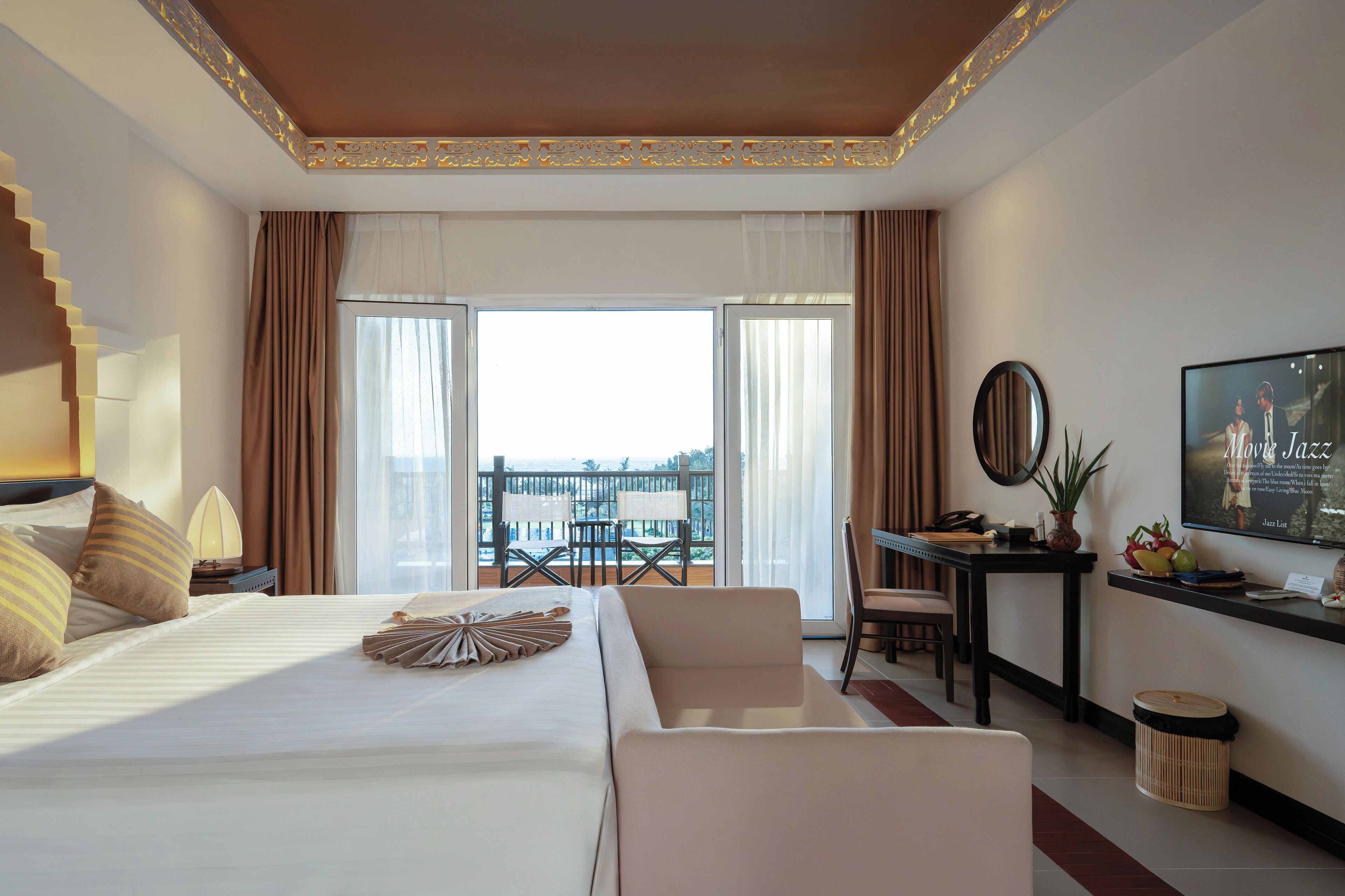 Habitación de hotel con una cama grande, un escritorio, una silla y un balcón con vistas.