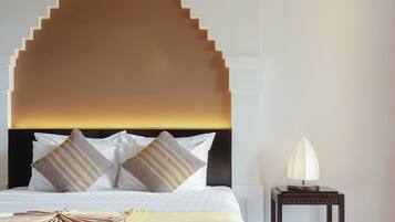 Una habitación de hotel con una cama, cabecera decorativa, mesita de noche y una lámpara.
