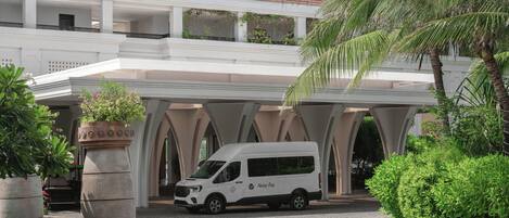 Un furgone bianco parcheggiato di fronte a un edificio con tetto in tegole rosse, colonne bianche e una galleria coperta.