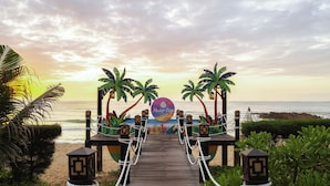 A wooden boardwalk leading to a beach with palm trees and a sign reading "Mune Bays." - Muine Bay Resort (Mui Ne)