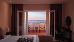 A hotel room with a bed, a small table, and a view of the sea through an open door. - Muine Bay Resort (Mui Ne)