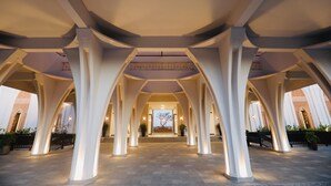 A corridor with white columns and a view of a building with a brick facade. - Muine Bay Resort (Mui Ne)