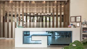 A reception area with a modern design, featuring a reception desk, a large plant, and framed certificates on the wall. - Hotel G7 Taipei (New Taipei City)