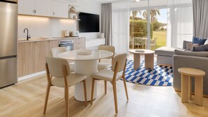 A modern kitchen with white cabinetry, a built-in oven, and a large window overlooking a garden. - The Sebel Palm Cove (Palm Cove)