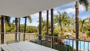 A covered outdoor area with a table and chairs, surrounded by palm trees and a pool. - The Sebel Palm Cove (Palm Cove)