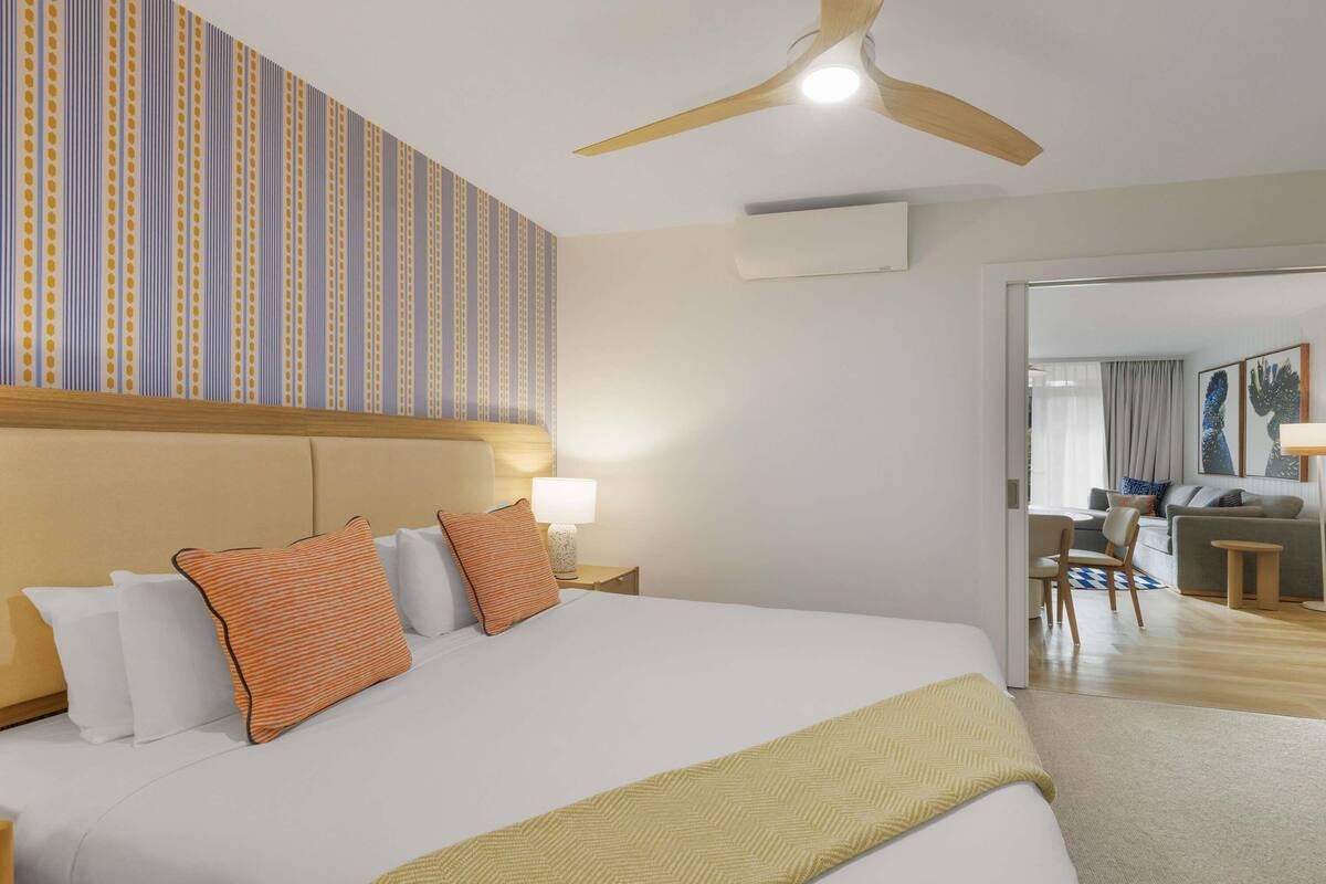Une chambre d’hôtel avec un grand lit, un ventilateur de plafond, un appareil de climatisation et une vue sur la salle à manger.