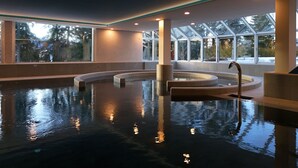 Une piscine intérieure au design moderne, dotée de grandes fenêtres et d’un espace détente.