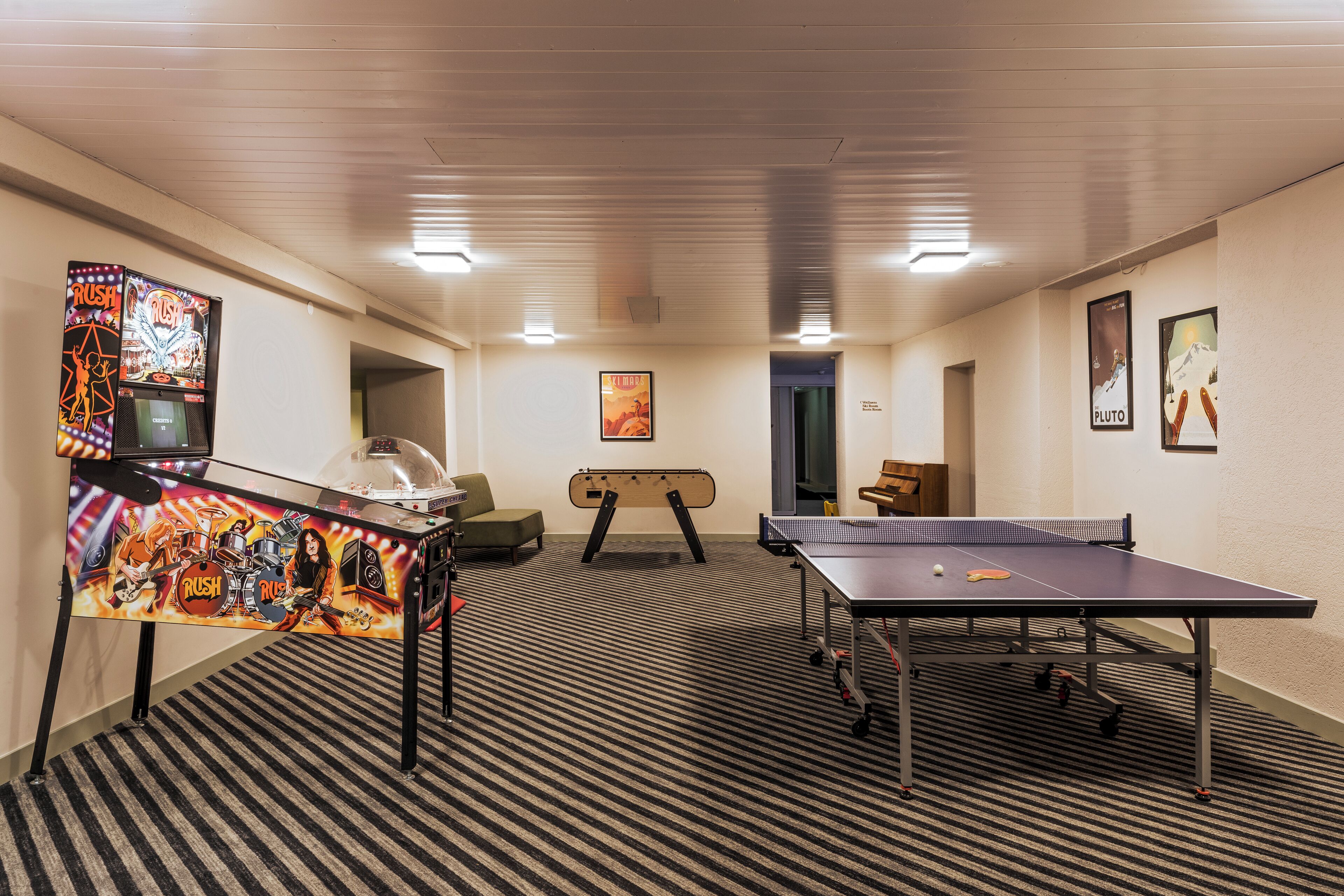 Une pièce avec une table de ping-pong, une batterie et une affiche de Pluton.