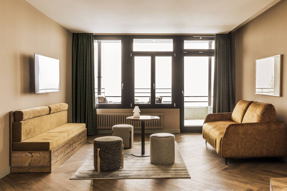 A modern living room with a sofa, ottoman, and a coffee table.