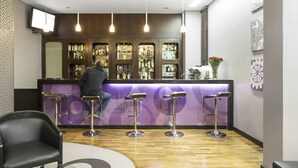 A bar area with a purple counter, multiple stools, and a bartender.