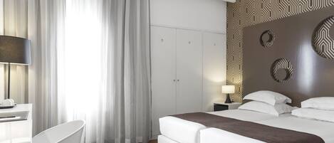 A modern hotel room with a large bed, a desk, and a chair.