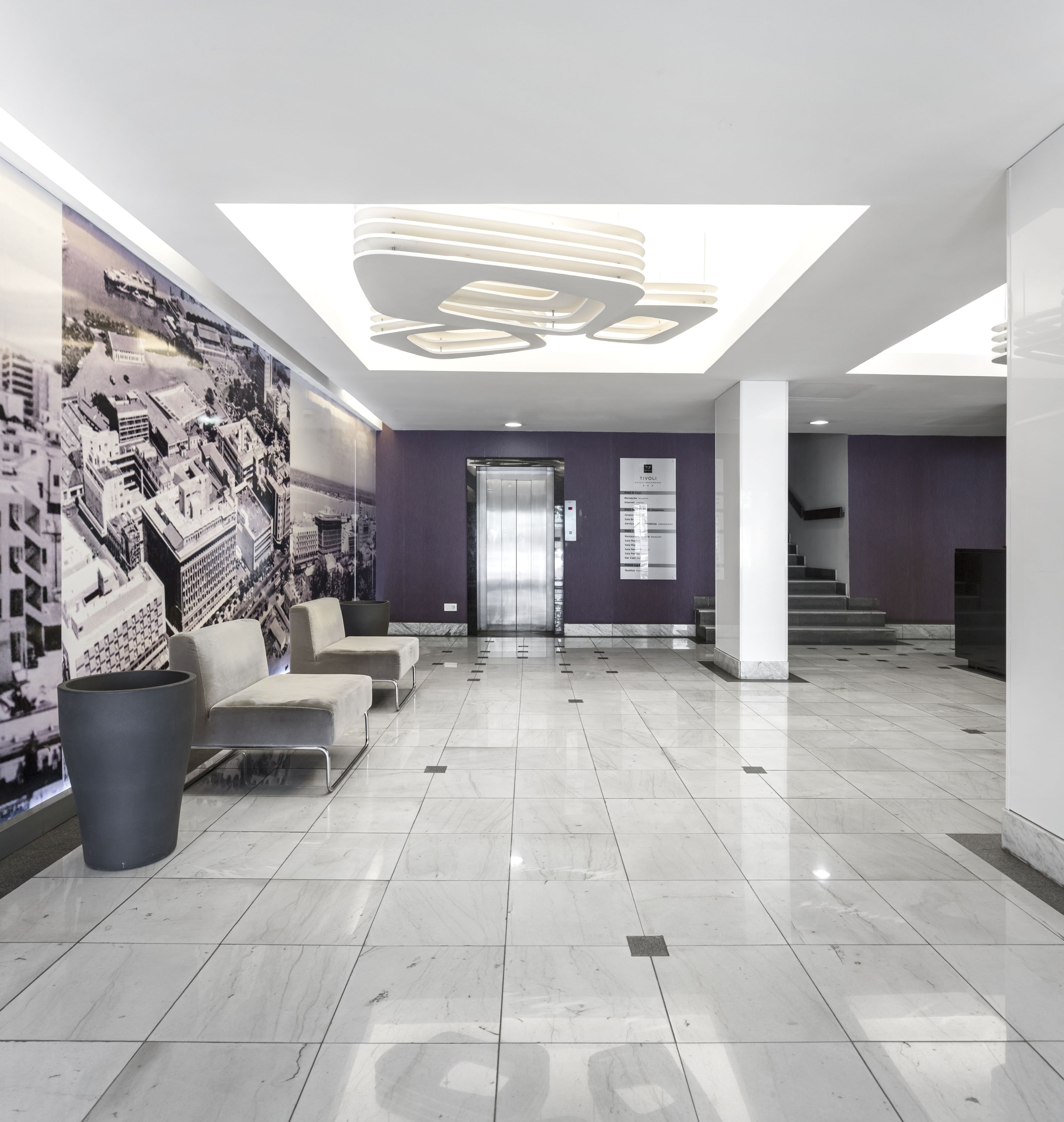 Un hall d’entrée moderne avec un haut plafond, un espace salon et un escalier.