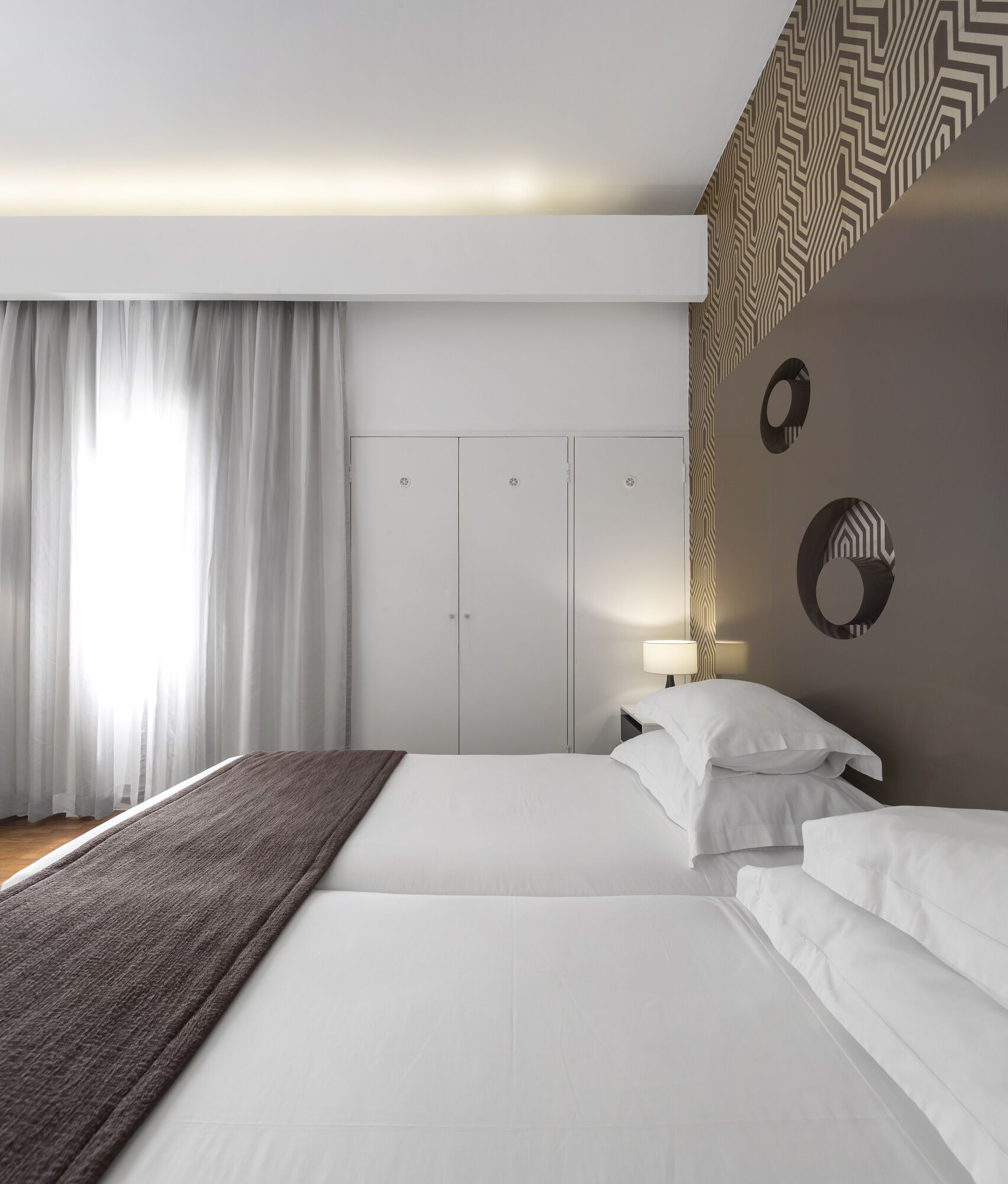 Ein modernes Hotelzimmer mit einem großen Bett, einem Nachttisch mit Lampe und einem Kleiderschrank.