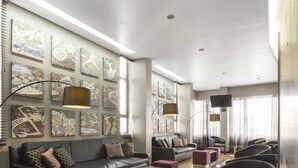A modern living room with a sofa set, ottomans, a glass coffee table, and a TV.