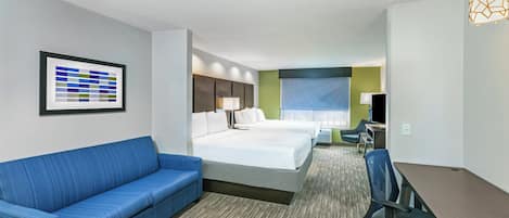 Una habitación de hotel con un sofá azul, dos camas, un escritorio y una silla.