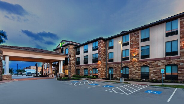 A hotel with a covered parking area, multiple floors, and a brick facade.