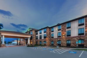 A hotel with a covered parking area, multiple floors, and a brick facade.