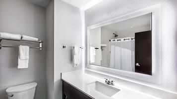 A modern bathroom with a white sink, a large mirror, and a toilet.