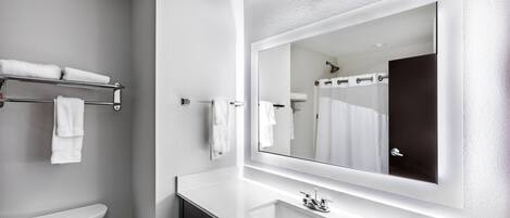 A modern bathroom with a white sink, a large mirror, and a toilet.